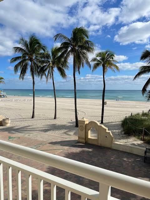 A balcony view overlooks a sandy beach with palm trees and the ocean under a sky — 901 S Surf Rd # 407, Hollywood FL 33019, HOLLYWOOD, FL