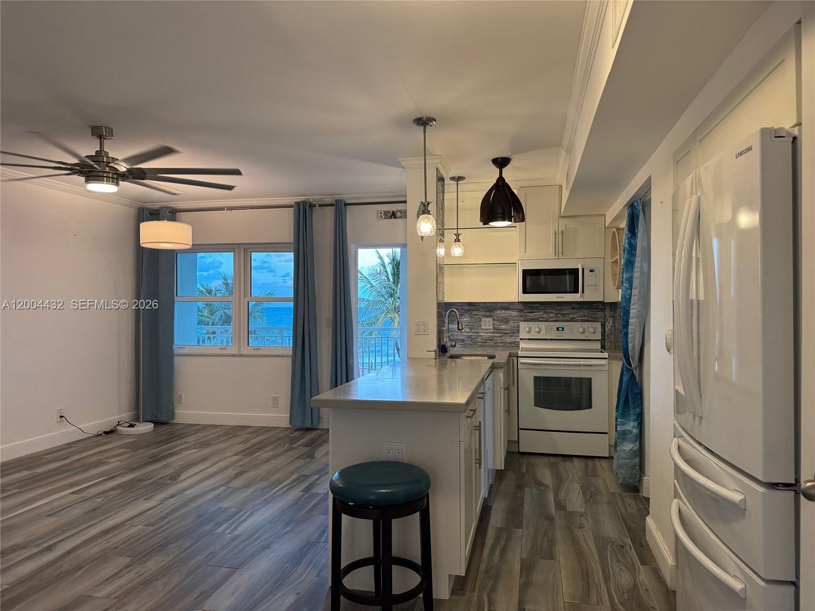 A kitchen with white cabinets and appliances opens into a living area with ocean views — 901 S Surf Rd # 407, Hollywood FL 33019, HOLLYWOOD, FL