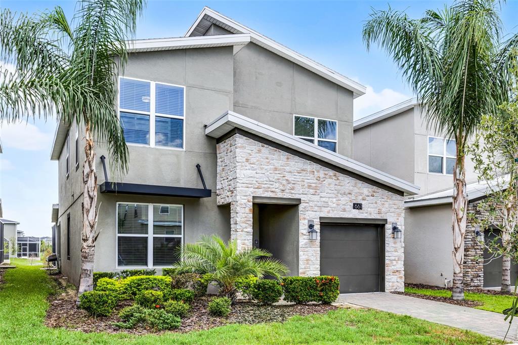 A two-story house with a gray stucco exterior, stone facade, and a single-car garage — 661 DROP SHOT DRIVE, DAVENPORT, FL