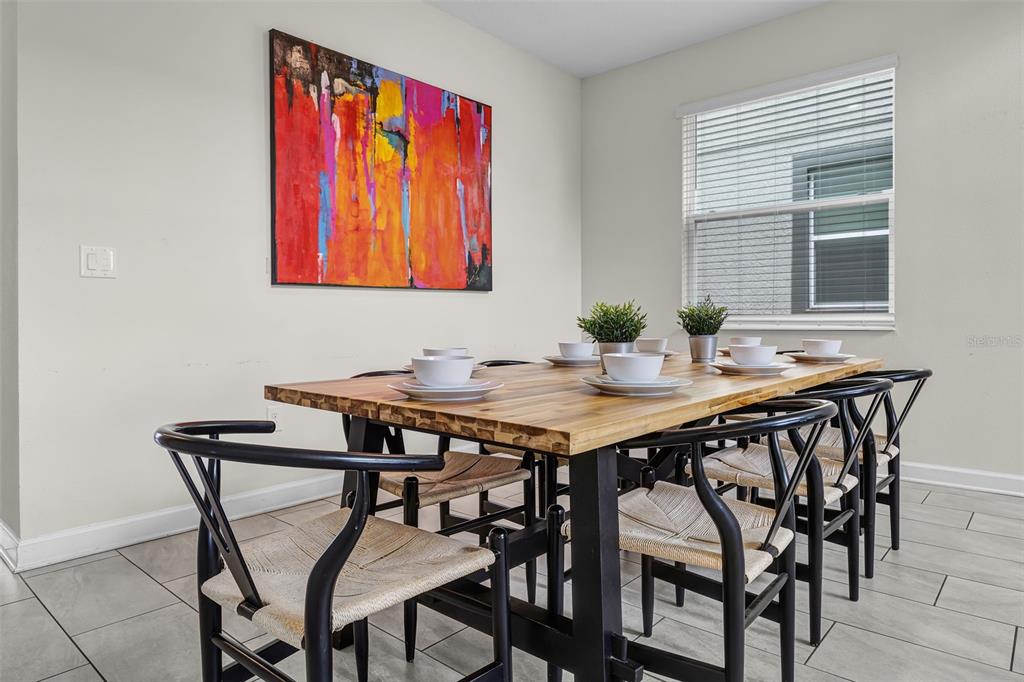 A dining room features a wooden table with black chairs and a large abstract painting — 661 DROP SHOT DRIVE, DAVENPORT, FL