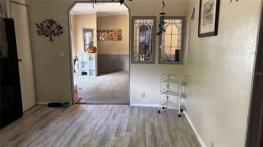 A dining area with wood-look flooring leads into a carpeted living space through an archway — 14902 NE 142ND STREET, WALDO, FL