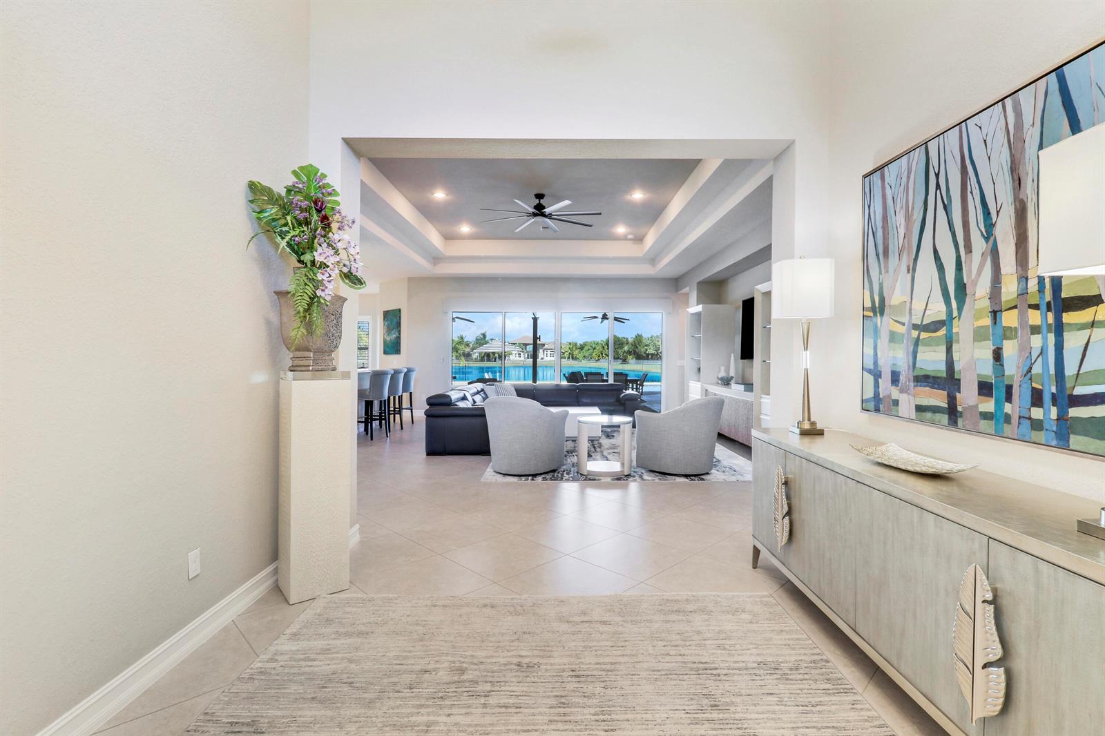 A bright foyer leads into a living room with a tray ceiling and lake view — 7754 Maywood Crest Drive, West Palm Beach FL 33412, WEST PALM BEACH, FL