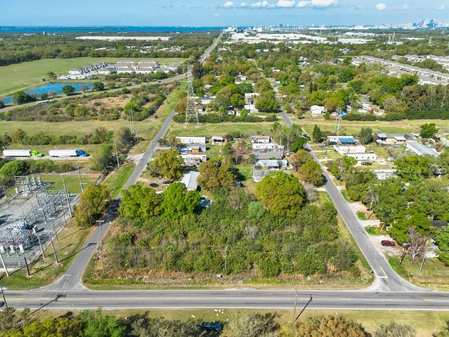 An aerial view shows a vacant, tree-covered lot situated between two roads and a power substation — 7623 S 51ST AVENUE, TAMPA, FL
