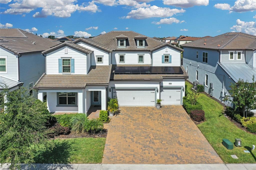 An aerial view of a two-story suburban house with a paver driveway and solar panels — 7537 WANDERING WAY, ORLANDO, FL