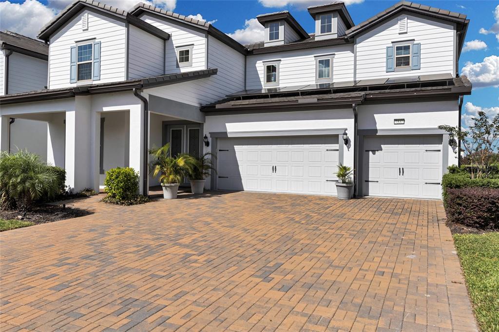 A two-story house with a brick paver driveway, three-car garage, and white siding — 7537 WANDERING WAY, ORLANDO, FL
