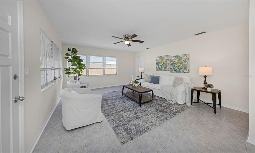 A living room features light tile floors, a white sofa, two armchairs, and a rug — 2814 TIFTON STREET S, GULFPORT, FL