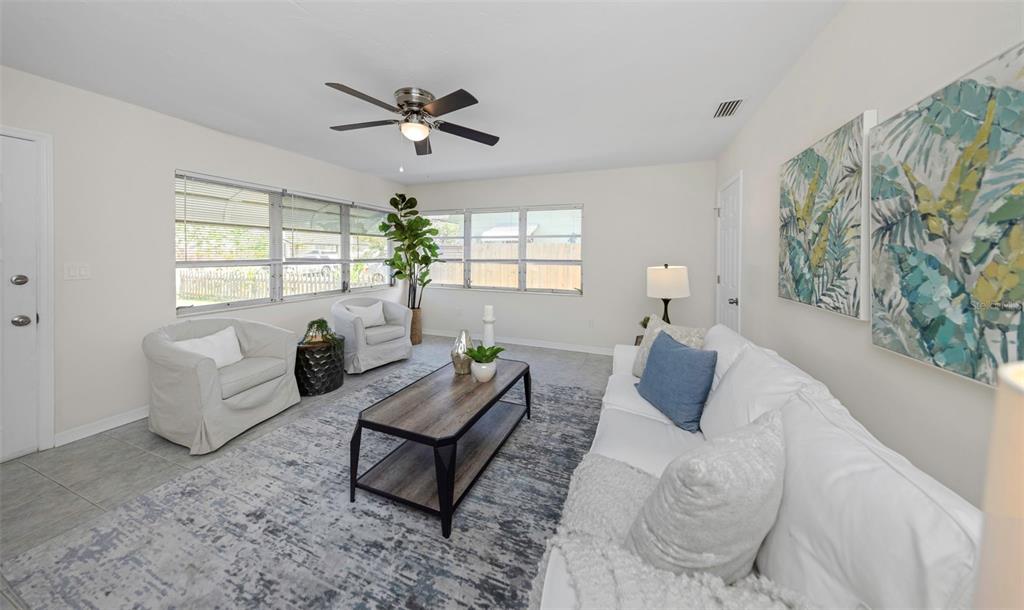 A bright living room features a white sofa, two armchairs, a coffee table, and tile flooring — 2814 TIFTON STREET S, GULFPORT, FL