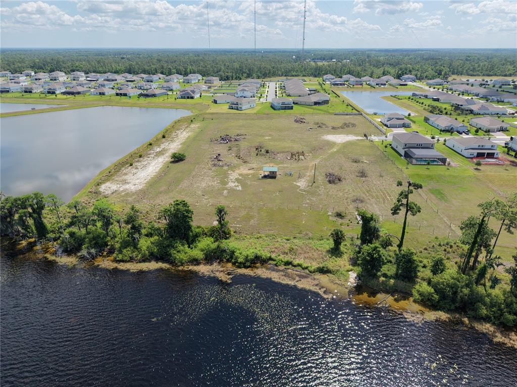 An aerial view shows a vacant, grassy waterfront lot with a small shed and trees — LAKE PICKETT RD, ORLANDO, FL
