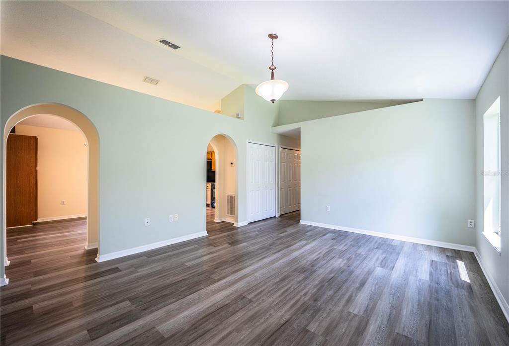 An empty room with light green walls, vaulted ceilings, and gray wood-look flooring — 241 GROVE BRANCH ROAD, WINTER HAVEN, FL