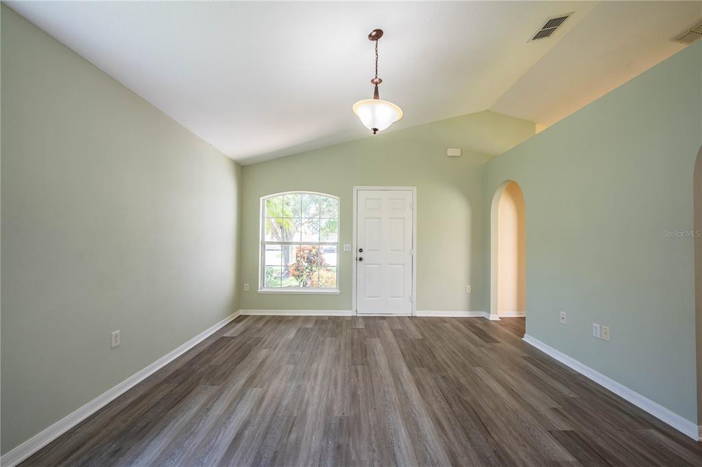 An empty room with light green walls, wood-look flooring, a vaulted ceiling, and a door — 241 GROVE BRANCH ROAD, WINTER HAVEN, FL