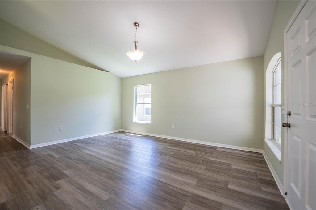 An empty room with light green walls, wood-look flooring, a vaulted ceiling, and two windows — 241 GROVE BRANCH ROAD, WINTER HAVEN, FL