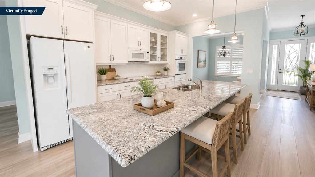 A kitchen with white cabinets, granite countertops, a gray island, and light wood flooring — 17 WATCHTOWER DRIVE, ORMOND BEACH, FL