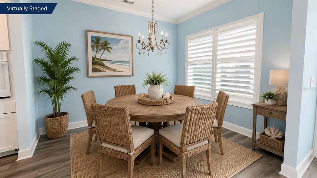 A dining room features a round wooden table, wicker chairs, and light blue walls — 17 WATCHTOWER DRIVE, ORMOND BEACH, FL