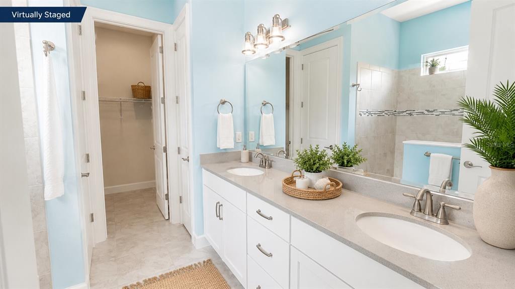 A bathroom features a double vanity with white cabinets, light countertops, and a walk-in closet — 17 WATCHTOWER DRIVE, ORMOND BEACH, FL