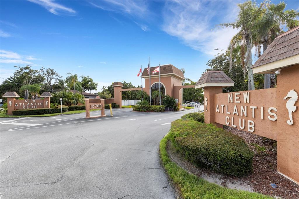 The entrance to the New Atlantis Club features a gated community sign and landscaping — 12760 INDIAN ROCKS ROAD UNIT 119, LARGO, FL