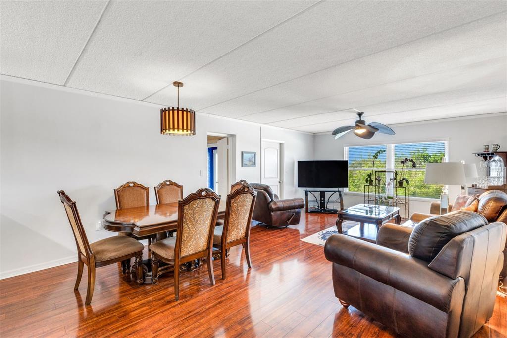 An open-concept living and dining area features wood flooring, a ceiling fan, and leather furniture — 12760 INDIAN ROCKS ROAD UNIT 119, LARGO, FL