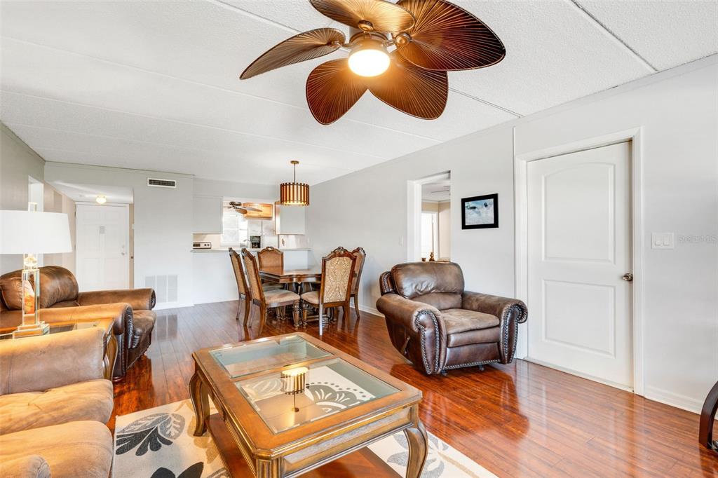 A dining area with a wooden table and chairs sits beneath a slatted pendant light — 12760 INDIAN ROCKS ROAD UNIT 119, LARGO, FL