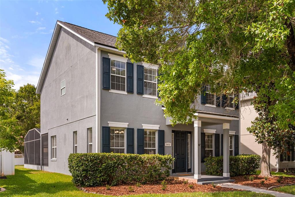 A two-story gray house with dark shutters, a front porch, and a landscaped front yard — 5032 BEACH RIVER ROAD, WINDERMERE, FL