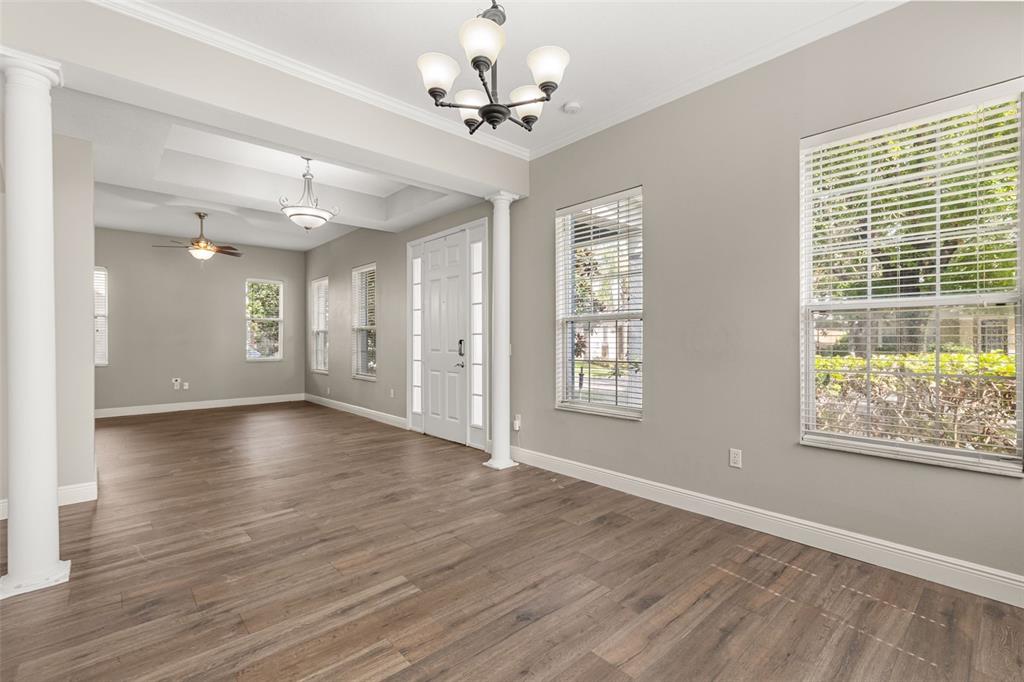 A bright room with wood-look flooring, white columns, a tray ceiling, and multiple windows — 5032 BEACH RIVER ROAD, WINDERMERE, FL