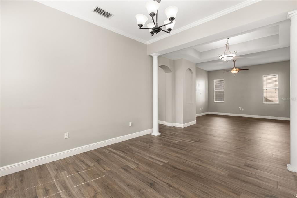 An open-concept living area features light gray walls, wood-look flooring, and two decorative chandeliers — 5032 BEACH RIVER ROAD, WINDERMERE, FL