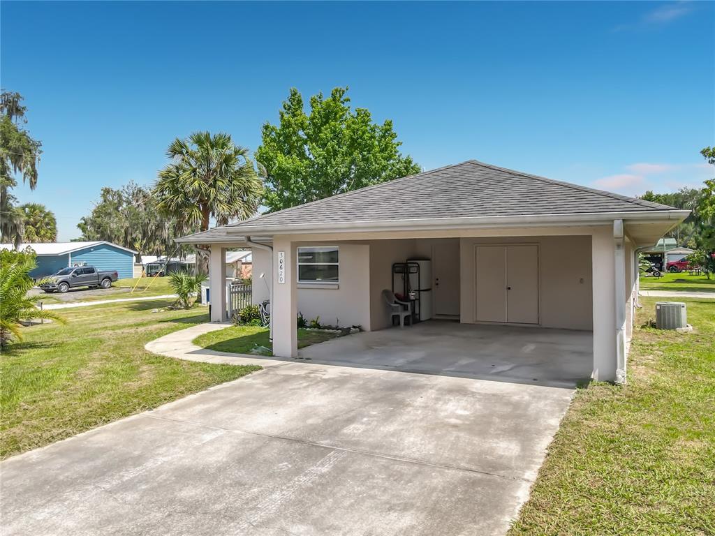 A single-story house features a concrete driveway leading to an attached carport and entrance — 30620 NE 95TH PLACE, FORT MC COY, FL