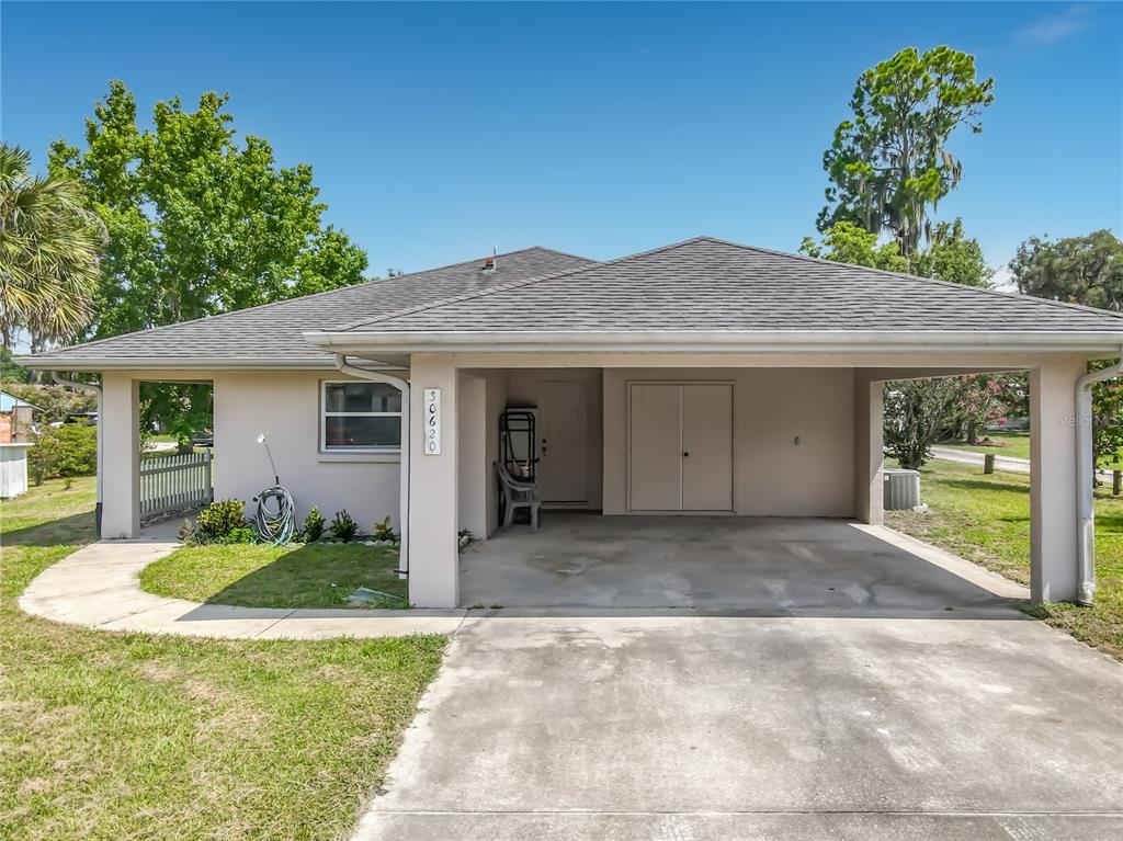 A single-story house features a concrete driveway, a covered carport, and a small front yard — 30620 NE 95TH PLACE, FORT MC COY, FL