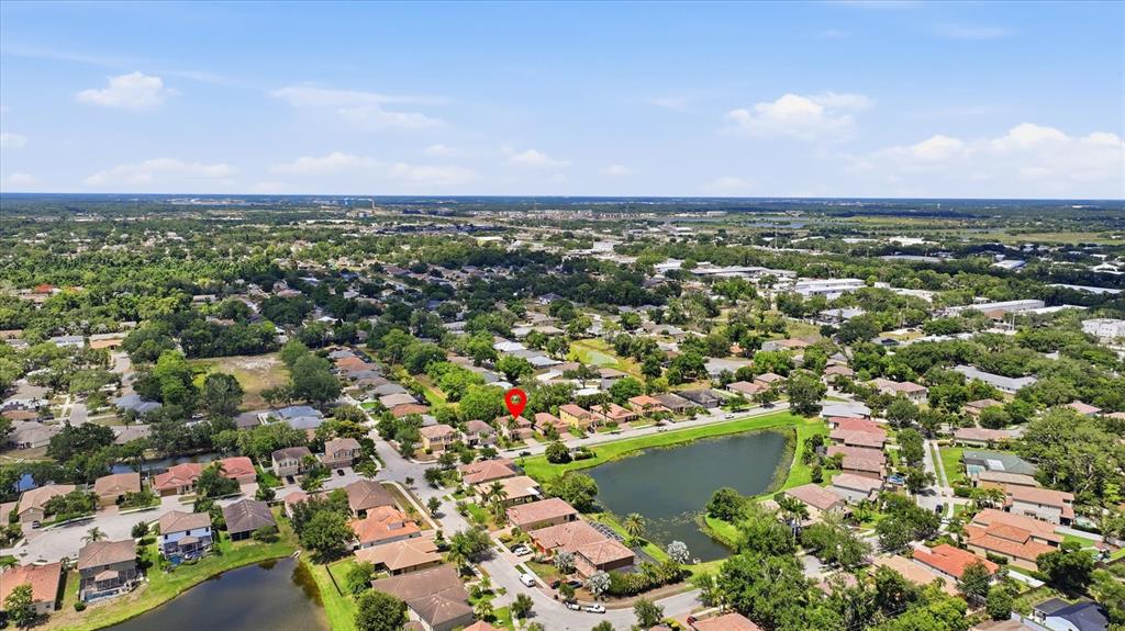 An aerial view shows a suburban neighborhood with houses surrounding a small lake — 5666 AARON COURT, SARASOTA, FL