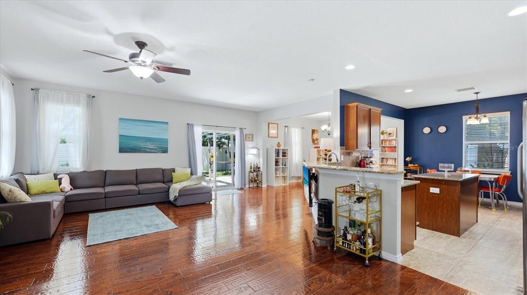 An open-concept living room and kitchen feature hardwood floors, a gray sectional, and blue walls — 5666 AARON COURT, SARASOTA, FL