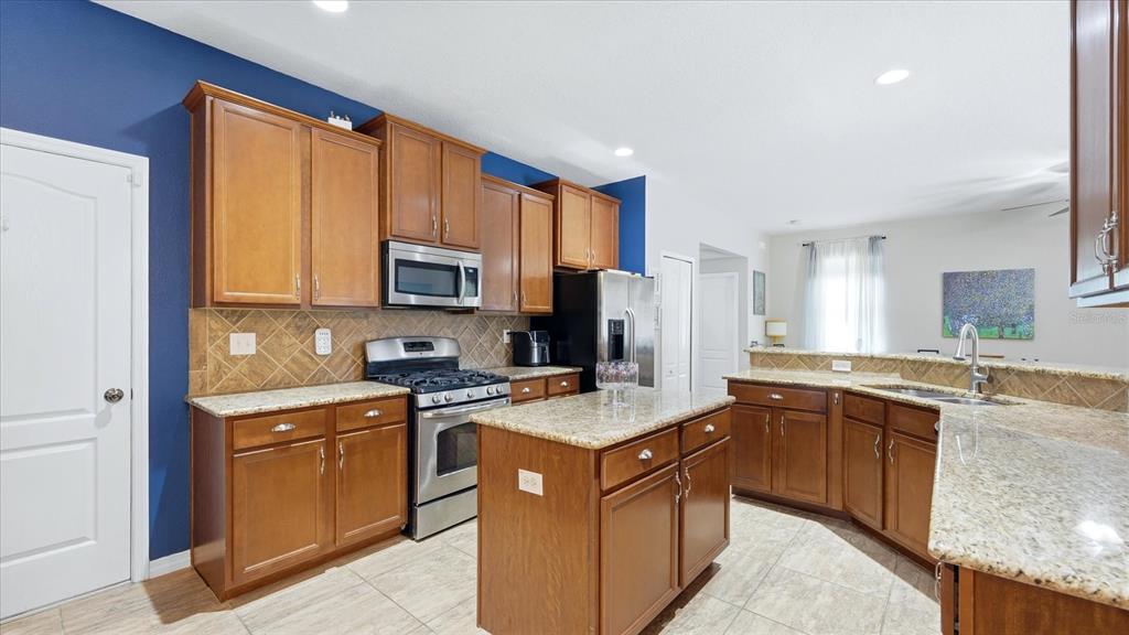 A kitchen features wood cabinets, granite countertops, stainless steel appliances, and a central island — 5666 AARON COURT, SARASOTA, FL