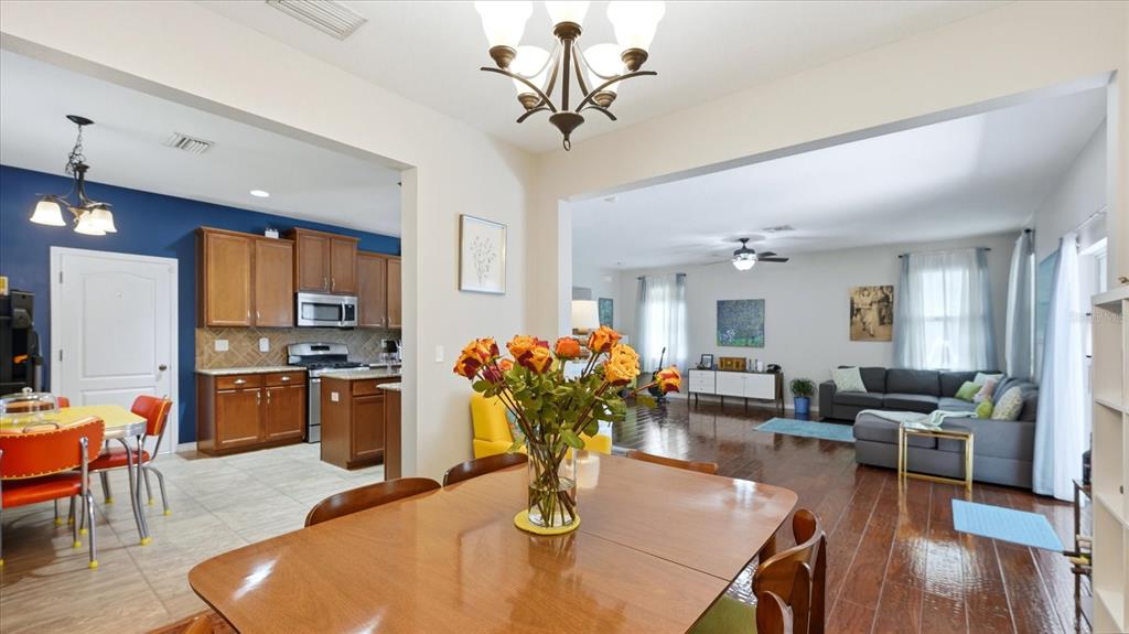 A dining area with a wooden table leads into a kitchen and a living room — 5666 AARON COURT, SARASOTA, FL