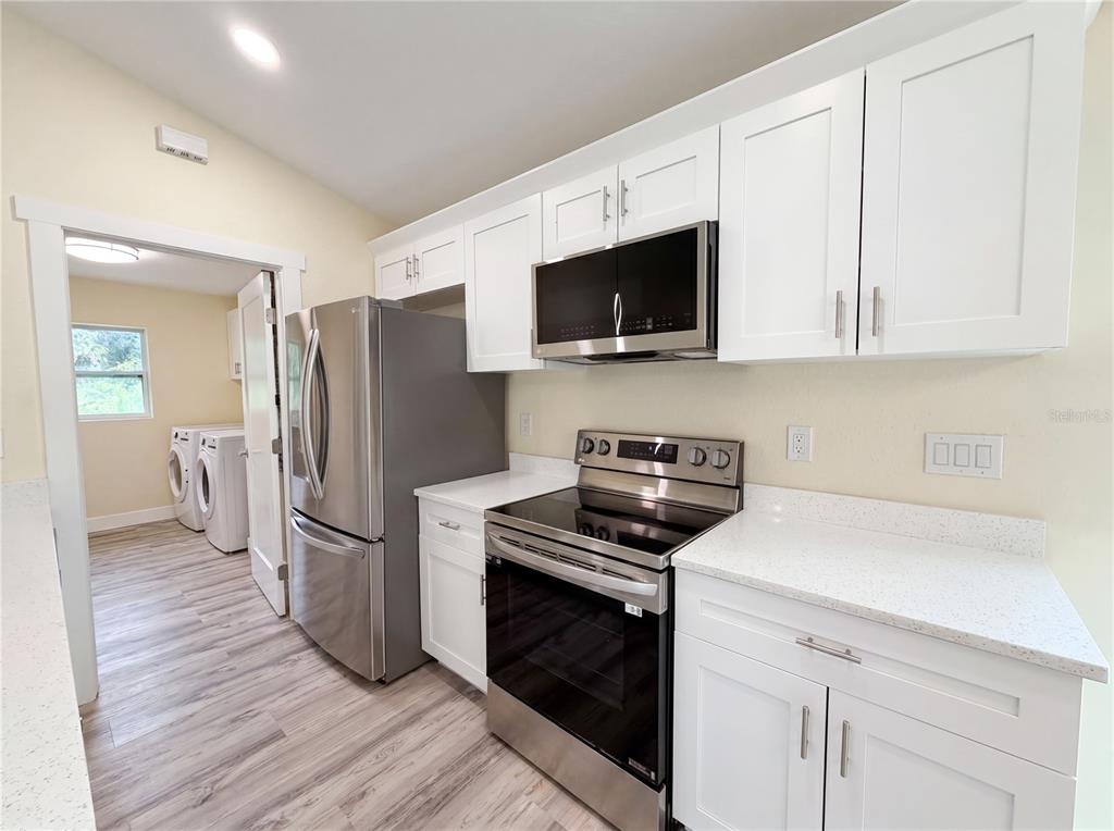 A kitchen features white cabinets, stainless steel appliances, and light-colored countertops — 1914 LANDAU AVENUE, NORTH PORT, FL