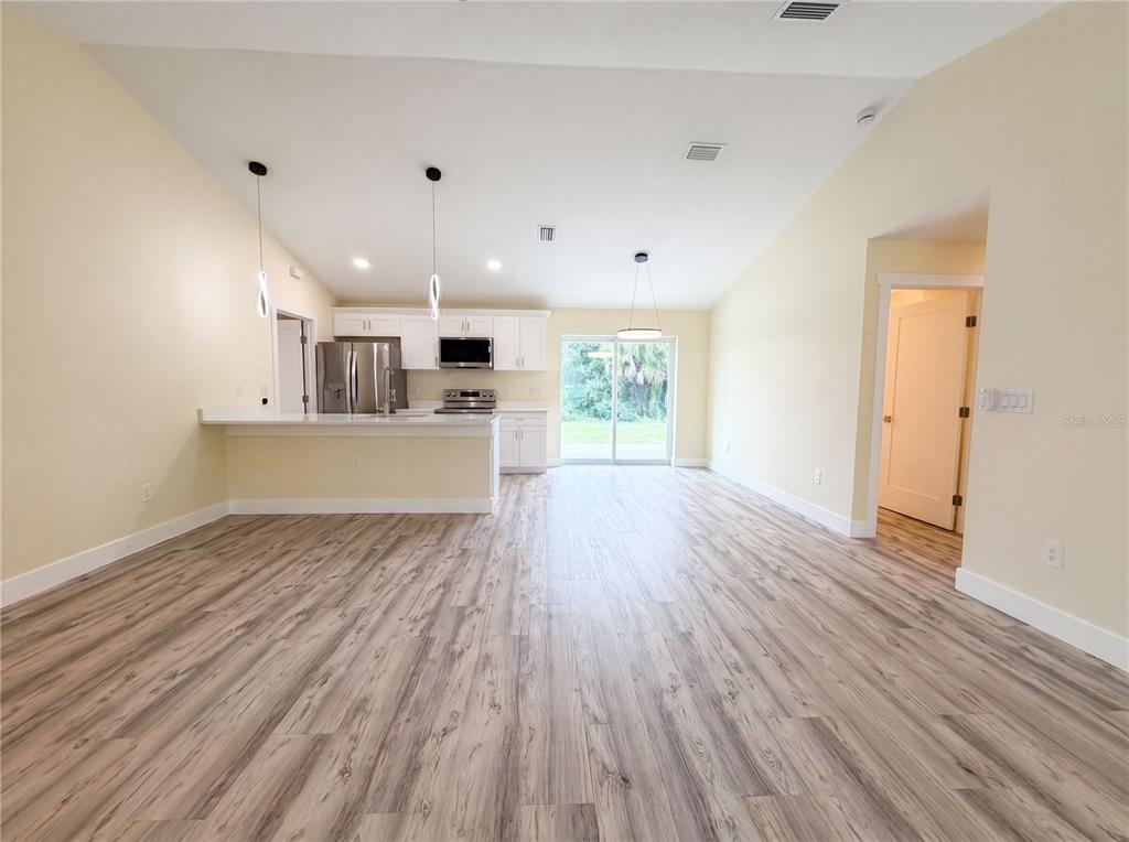 A kitchen with white cabinets and a breakfast bar opens into a spacious living area — 1914 LANDAU AVENUE, NORTH PORT, FL