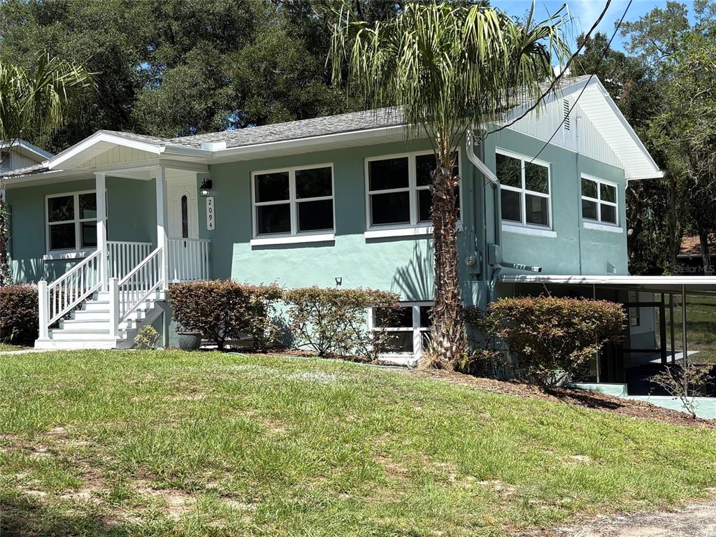 A light green single-story house with white trim, a front porch, and a palm tree — 2094 PENN DRIVE, DELAND, FL