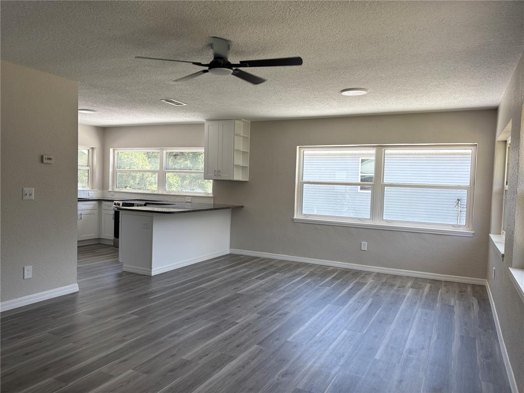 An open-concept kitchen and living area features gray wood-look flooring and white cabinetry — 2094 PENN DRIVE, DELAND, FL