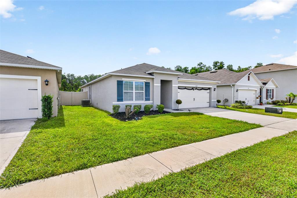 A single-story suburban house with a gray exterior, blue shutters, and a two-car garage — 1351 FOX SQUIRREL DRIVE, DAVENPORT, FL