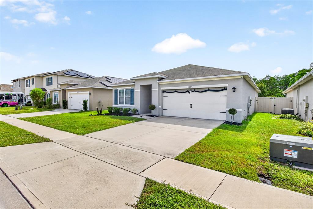 A single-story suburban house with a two-car garage, concrete driveway, and green lawn — 1351 FOX SQUIRREL DRIVE, DAVENPORT, FL