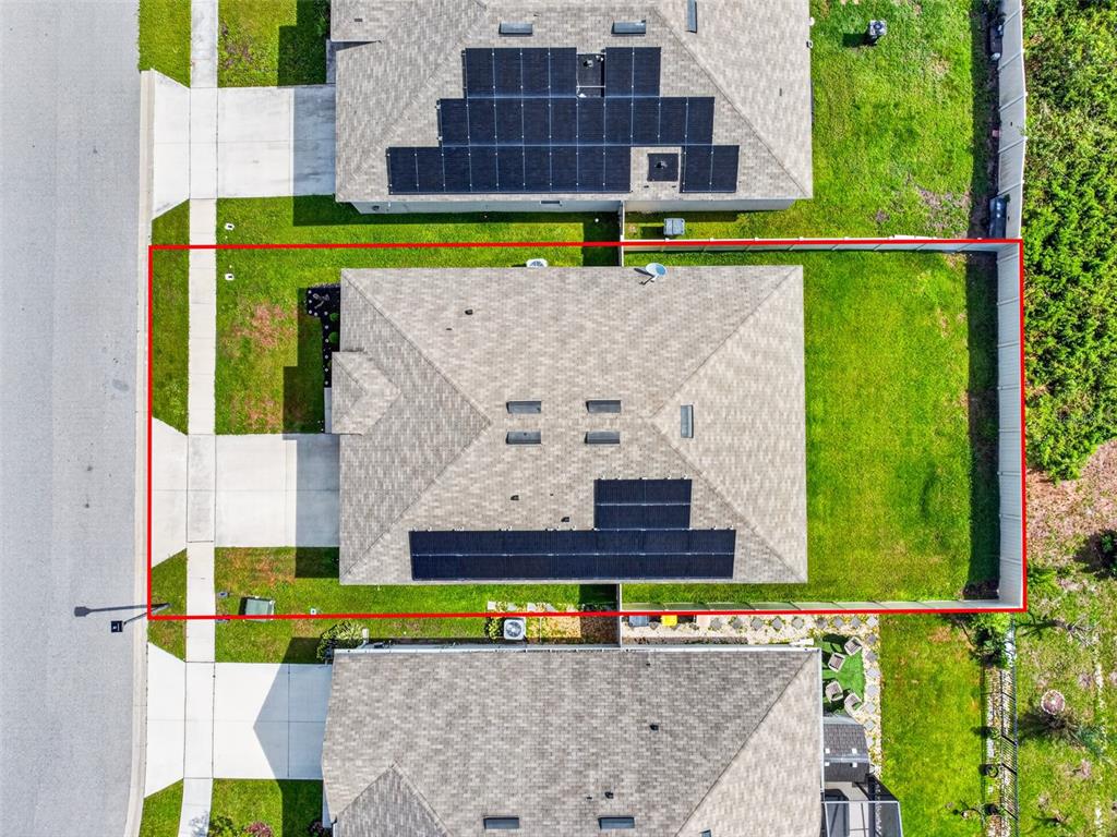 An aerial view shows a single-family home with solar panels on the roof and a backyard — 1351 FOX SQUIRREL DRIVE, DAVENPORT, FL