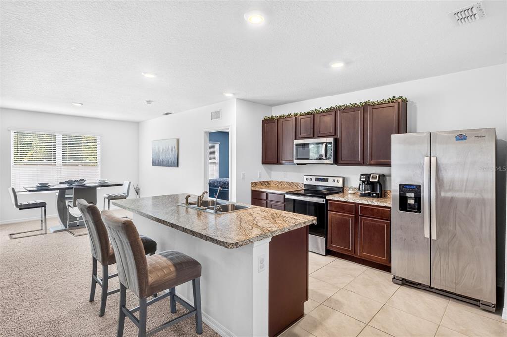 A kitchen with dark wood cabinets, granite countertops, and a center island with bar seating — 1351 FOX SQUIRREL DRIVE, DAVENPORT, FL