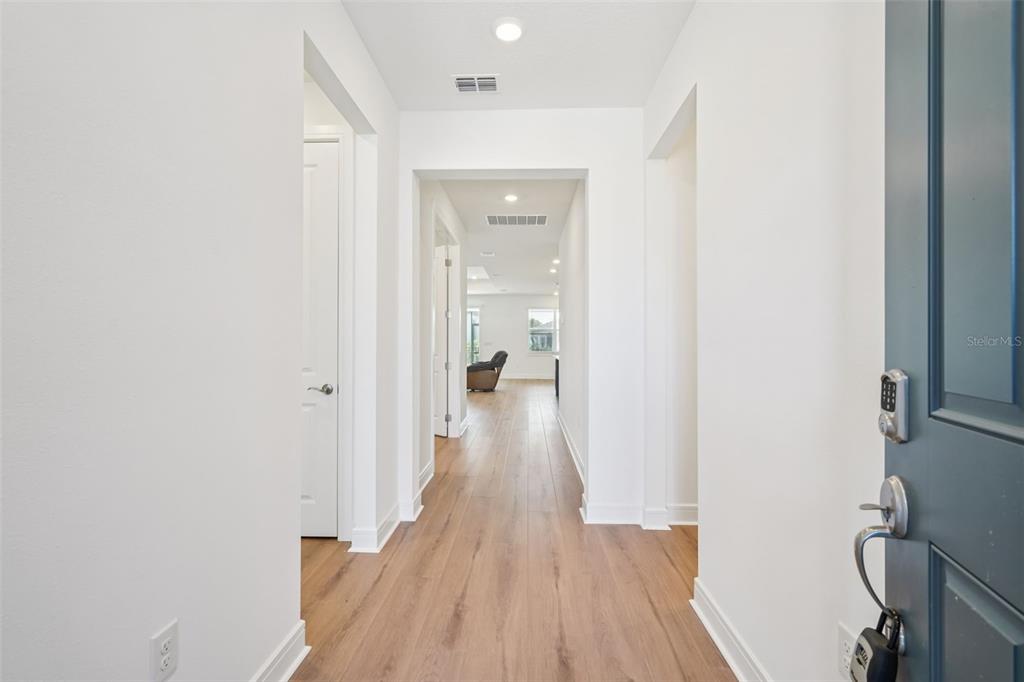 A view from an entryway looking down a hallway with wood-look flooring toward a living area — 5236 SW 88TH CIRCLE, OCALA, FL