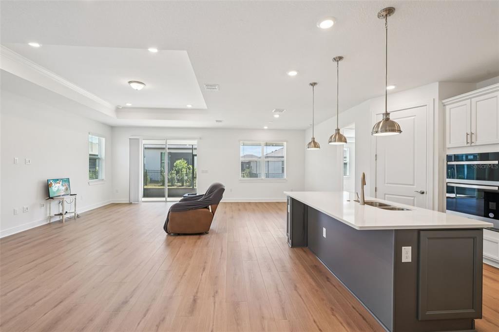 A spacious open-concept kitchen and living area features light wood flooring and a center island — 5236 SW 88TH CIRCLE, OCALA, FL