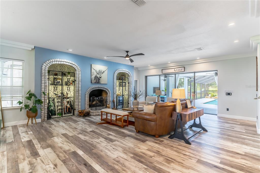 A living room features a blue wall with arched brick accents, a fireplace, and wood-look flooring — 23100 SE HIGHWAY 42, UMATILLA, FL