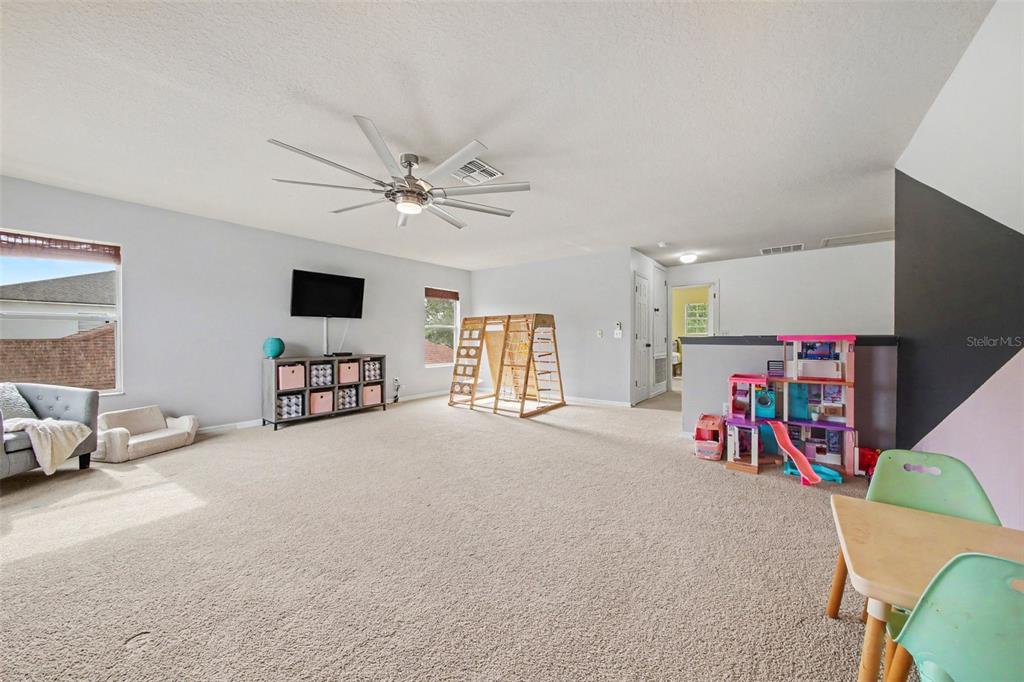 A carpeted playroom features a ceiling fan, a television, a wooden climbing frame, and toys — 13626 PHOENIX, ORLANDO, FL
