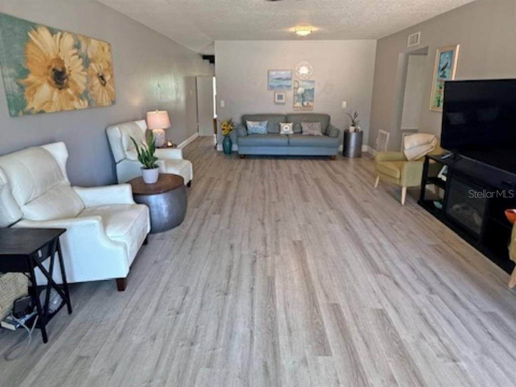 A kitchen features white cabinets, stainless steel appliances, a tiled backsplash, and light wood flooring — 2262 SWEDISH DRIVE UNIT 14, CLEARWATER, FL