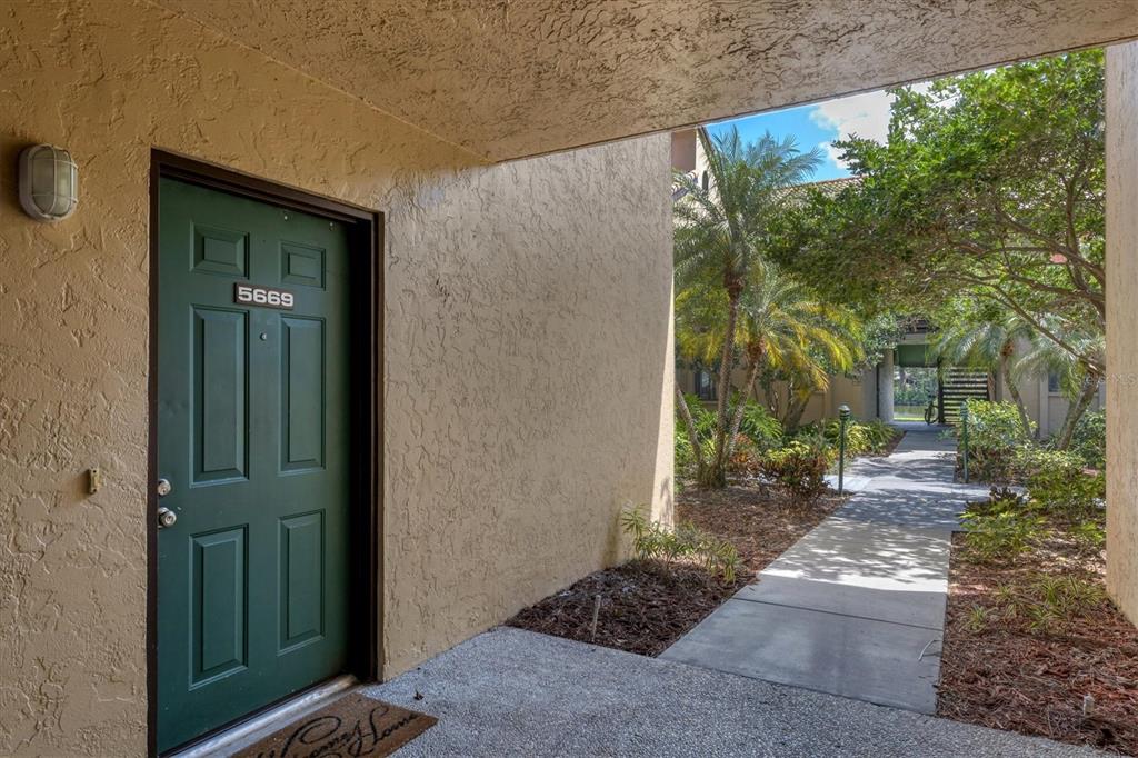 A green front door with the number 5669 is set into a tan stucco exterior wall — 5669 ASHTON LAKE DRIVE UNIT 1, SARASOTA, FL