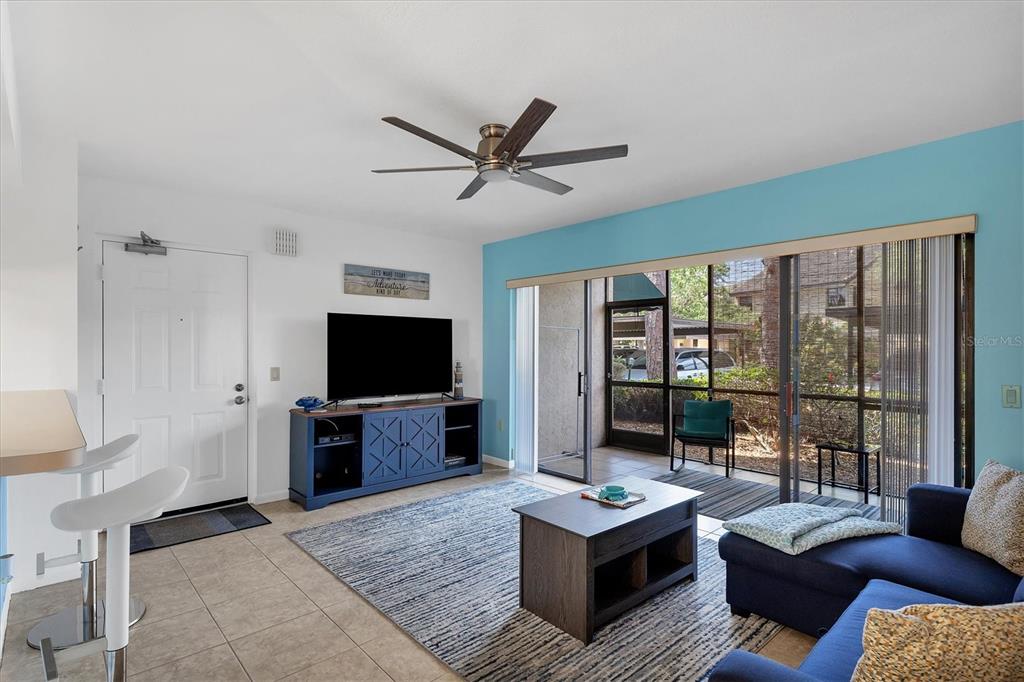 A living room features a blue accent wall, sliding glass doors, and a ceiling fan — 5669 ASHTON LAKE DRIVE UNIT 1, SARASOTA, FL