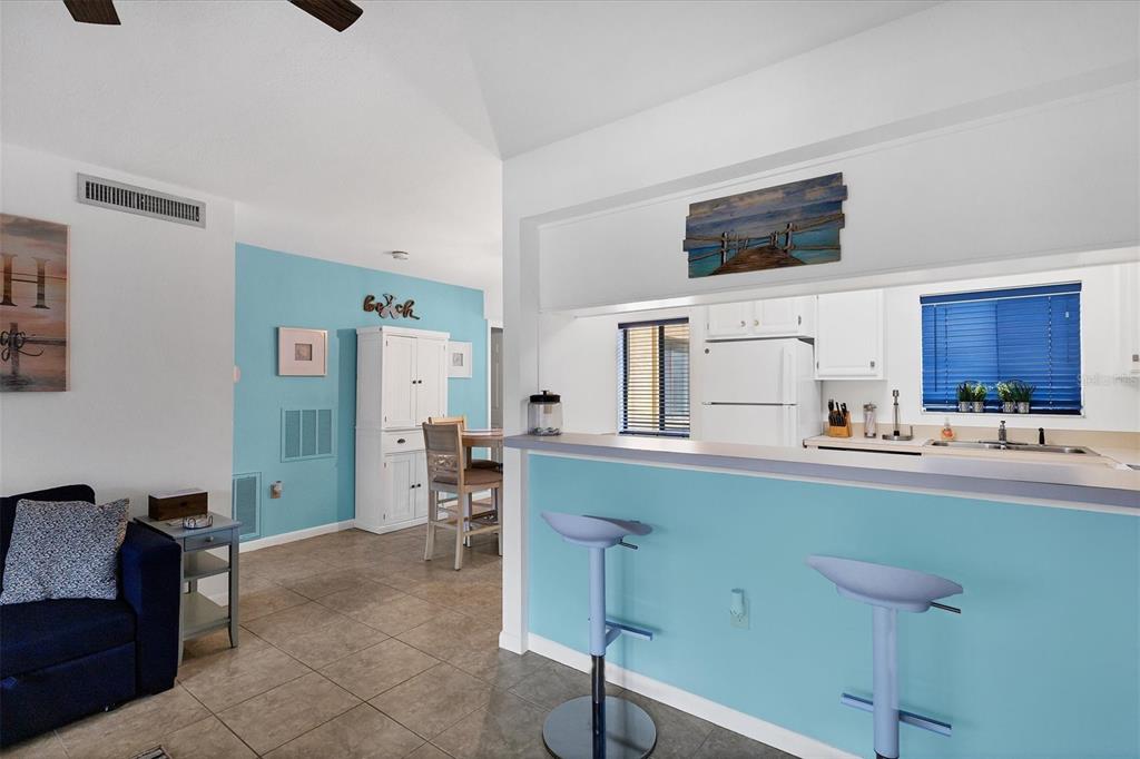 A kitchen with a breakfast bar and blue walls opens into a dining area — 5669 ASHTON LAKE DRIVE UNIT 1, SARASOTA, FL