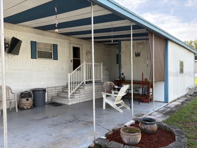 A covered patio features a concrete floor, white siding, a staircase, and outdoor furniture — 29218 HECKLEMAN STREET, BROOKSVILLE, FL