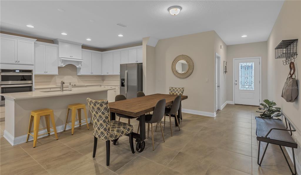 A kitchen with white cabinets, a wooden dining table, and a tiled floor — 7538 SEA OAK COURT, PARRISH, FL