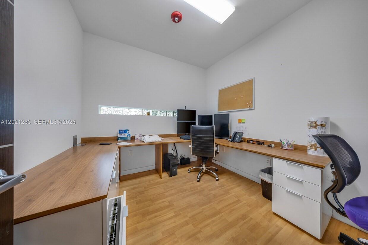 An office features an L-shaped wooden desk, two computer monitors, and a rolling chair — 99 W 49th St, Hialeah FL 33012, HIALEAH, FL
