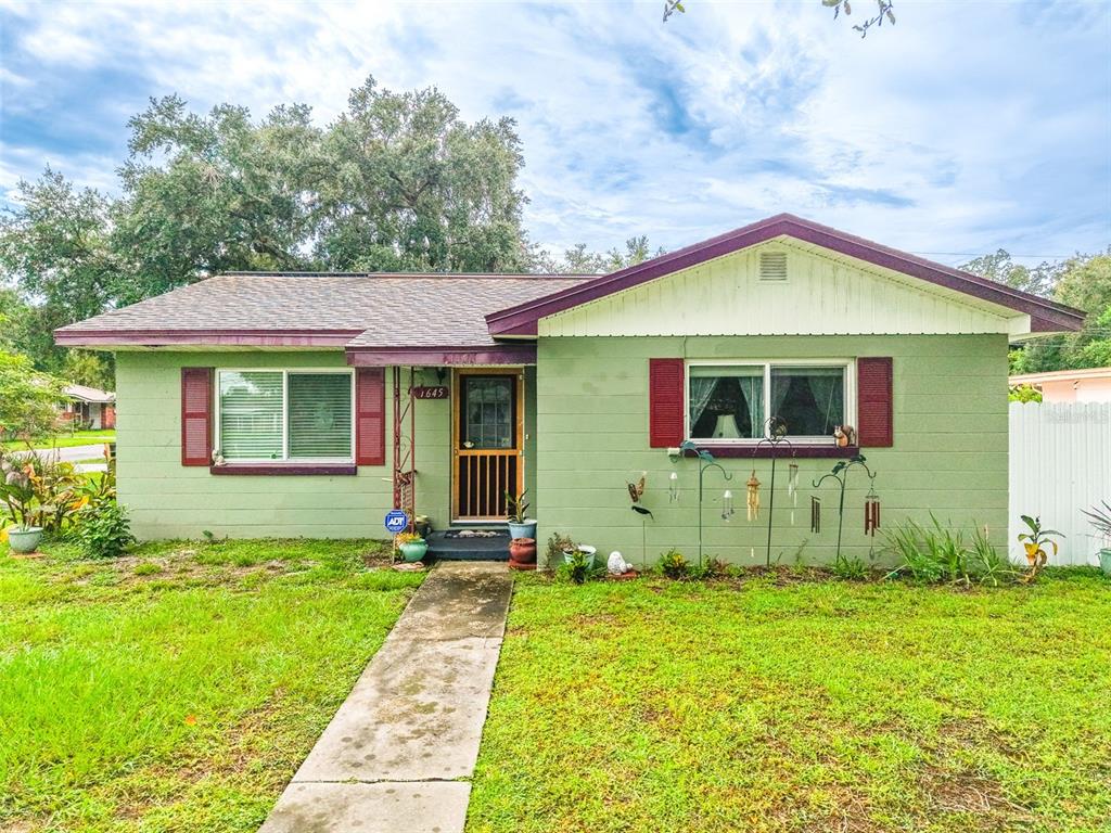 A single-story house with green siding, a dark roof, and red shutters on the windows — 1645 HUNTINGTON STREET, LAKELAND, FL